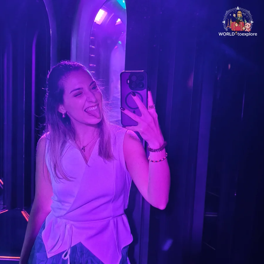 Cristina taking a selfie in the mirror, tongue out, in a purple-lit room at Neonia