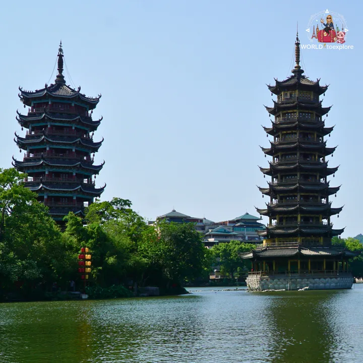View of the Sun and Moon Pagodas by Shanhu Lake, one dark-toned and the other golden, reflected in the water