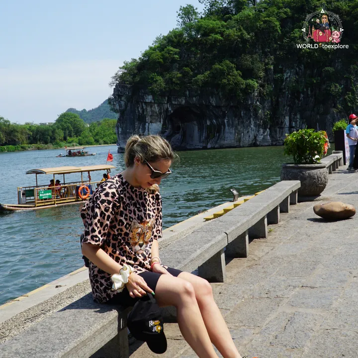 Cristina sitting by the water, with Elephant Trunk Hill in the background, in Guilin