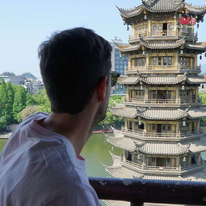 Man looking at the Sun Pagoda up close, with the lake and the city in the background