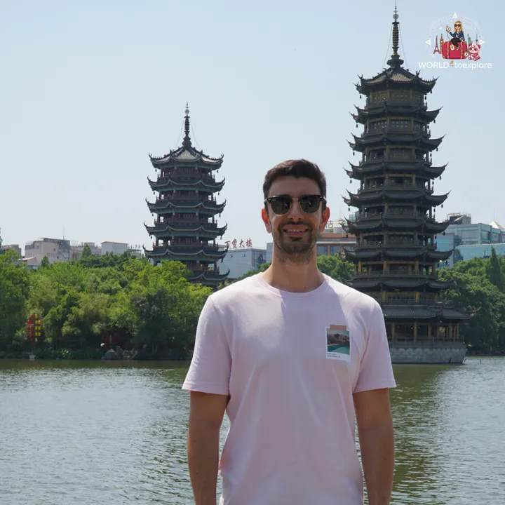 Man standing in front of the two pagodas by Shanhu Lake, during the day