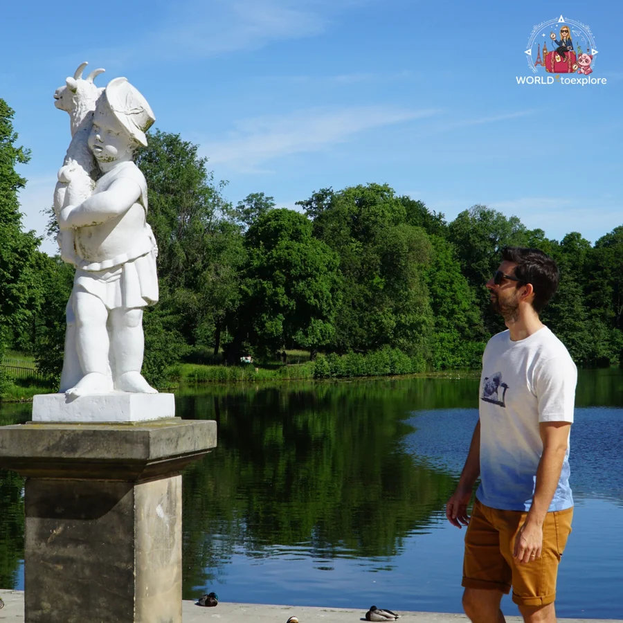 White statue of a child figure by the lake, with a man beside it