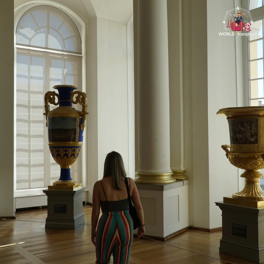 Woman seen from behind in a white room with large windows and two large decorative vases