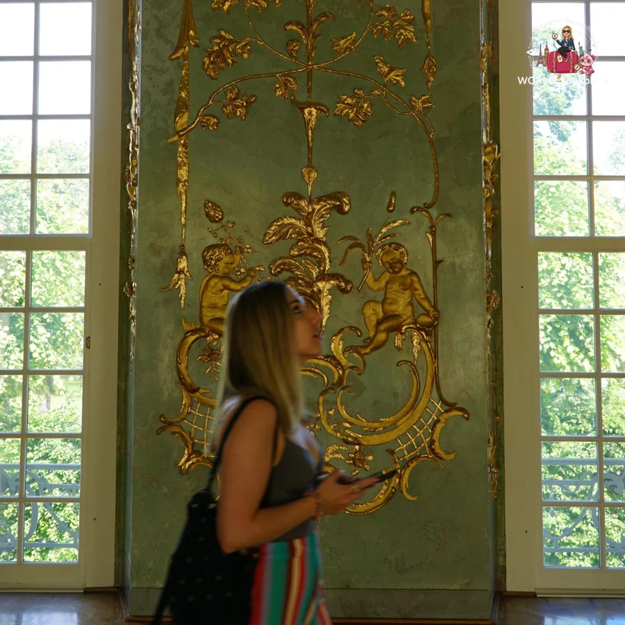 Woman looking at a wall with golden relief ornaments, between two windows