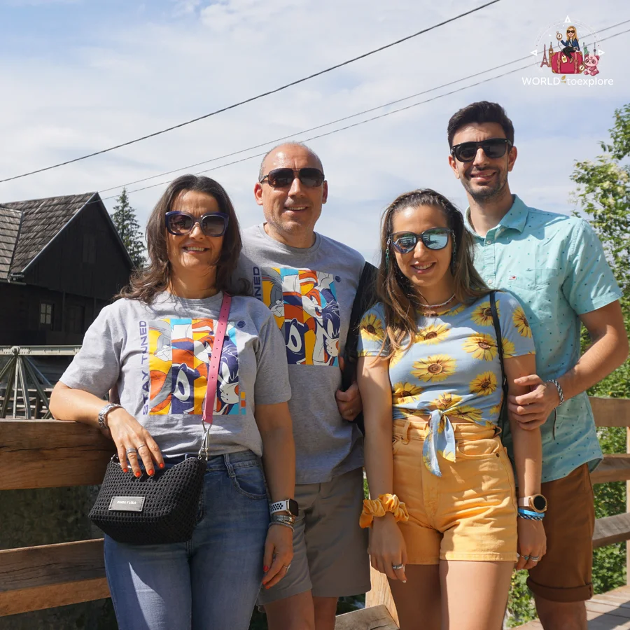 Cristina and her partner with two other people on the wooden bridge in Rastoke, with a mill with a wooden roof behind