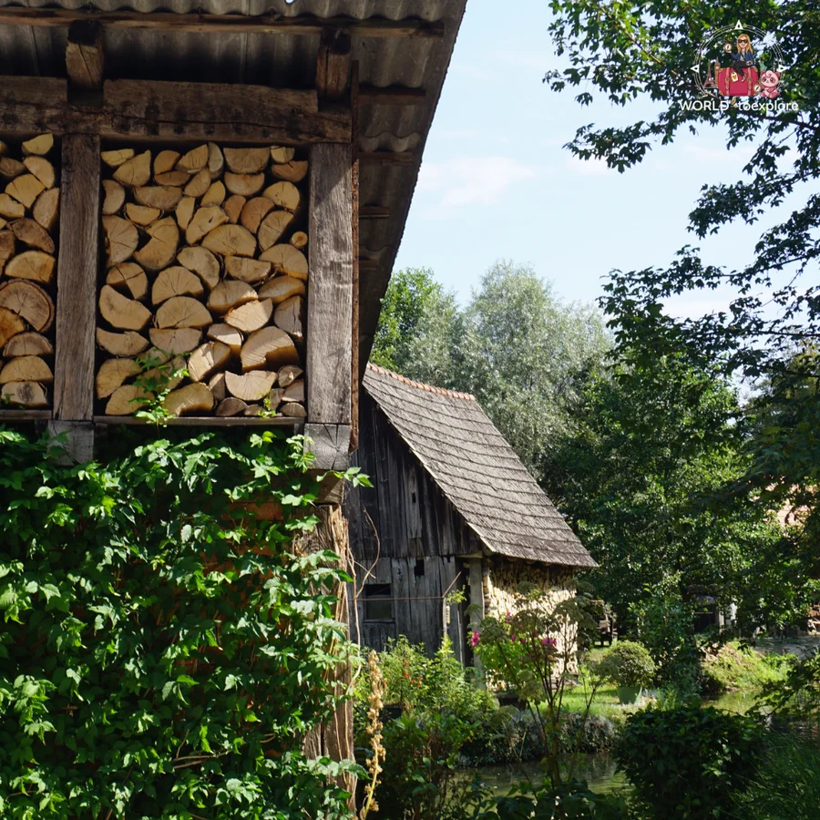 Wooden shelter with stacked firewood in Rastoke and, beside it, an old mill with a wooden shingle roof