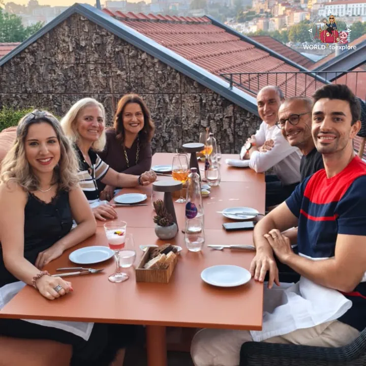 The group of six at the long table on the RENATA terrace, with drinks and bread on the table and Porto behind
