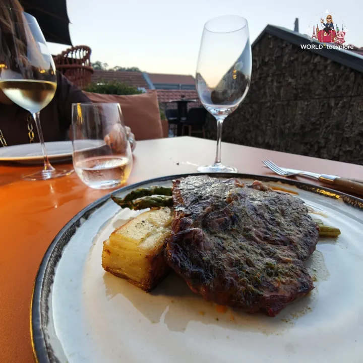 The Ribeye Minhota, grilled, with potato gratin and green asparagus, on the terrace at dusk
