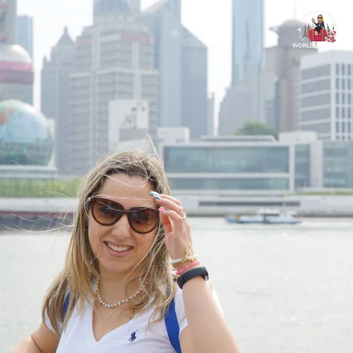 The author by the Huangpu River, with the skyscrapers of Pudong blurred behind her