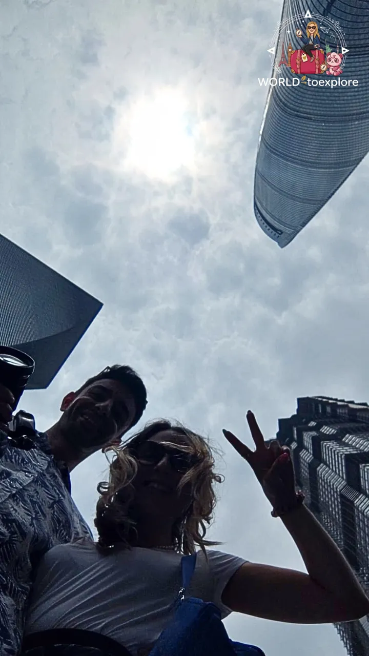 Low-angle selfie of the couple, with the Shanghai Tower rising into the sky