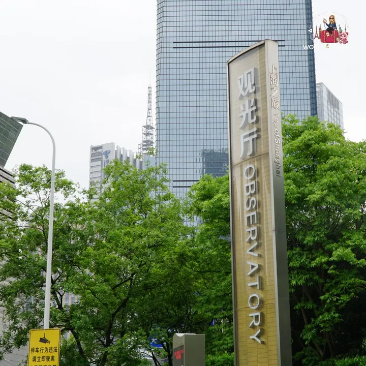 Golden totem 'Top of Shanghai Observatory' at the entrance, with the glass base of the Shanghai Tower behind it