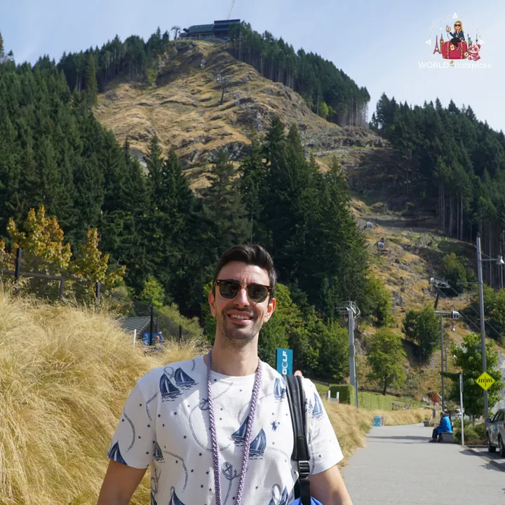 A smiling man on the Tiki Trail with Bob’s Peak and the Skyline Gondola cabins in the background