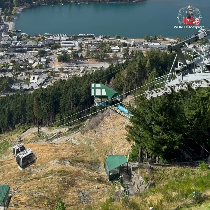 Two Skyline Gondola cabins climbing the hillside, with the mid-station and Lake Wakatipu in the background