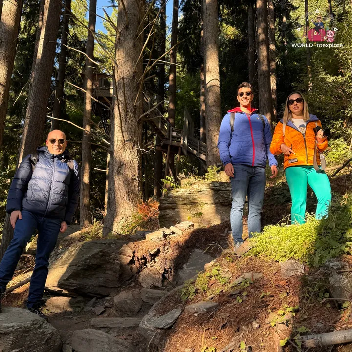 A group of three posing on the Tiki Trail, next to a wooden platform suspended among the trees