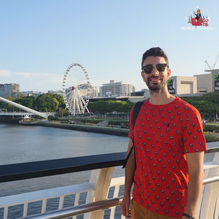 On a walkway over the river, with the Wheel of Brisbane and South Bank in the background