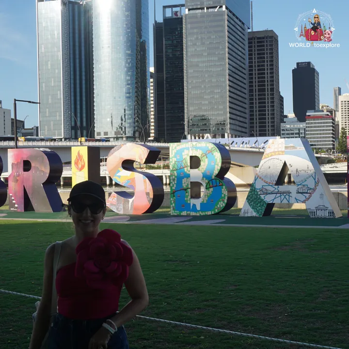 Posing in front of the 'BRISBANE' sign, with the colourful illustrated letters and the skyscrapers behind