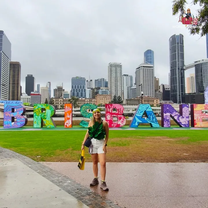 Posing in front of the 'BRISBANE' sign on a cloudy day, with the skyline behind