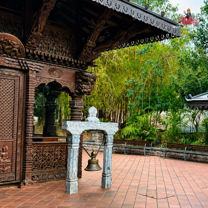 Detail of the Nepal Peace Pagoda, with a bronze bell hanging from a stone structure and the wood carvings alongside