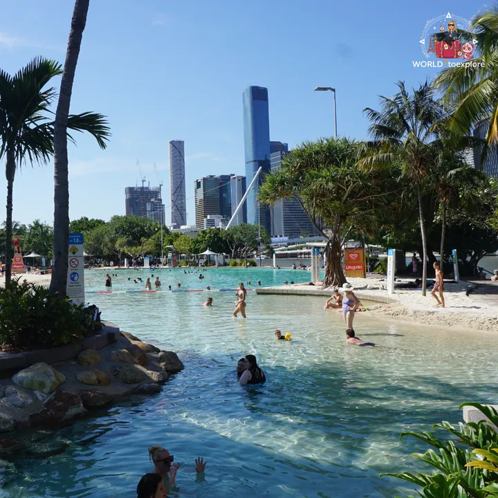 The Streets Beach lagoon with the Brisbane skyscrapers behind, surrounded by palm trees and golden sand