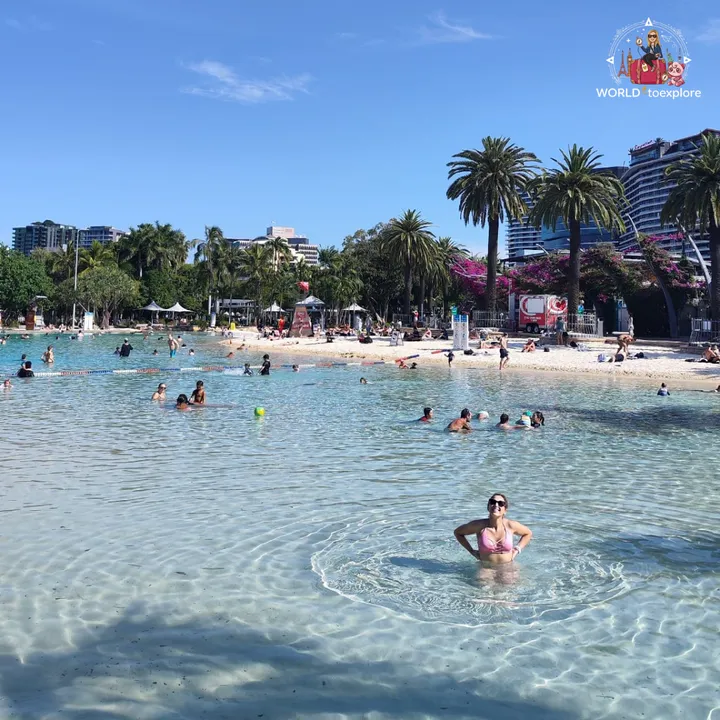 Standing in the water at Streets Beach, with the sand, palm trees and buildings in the background
