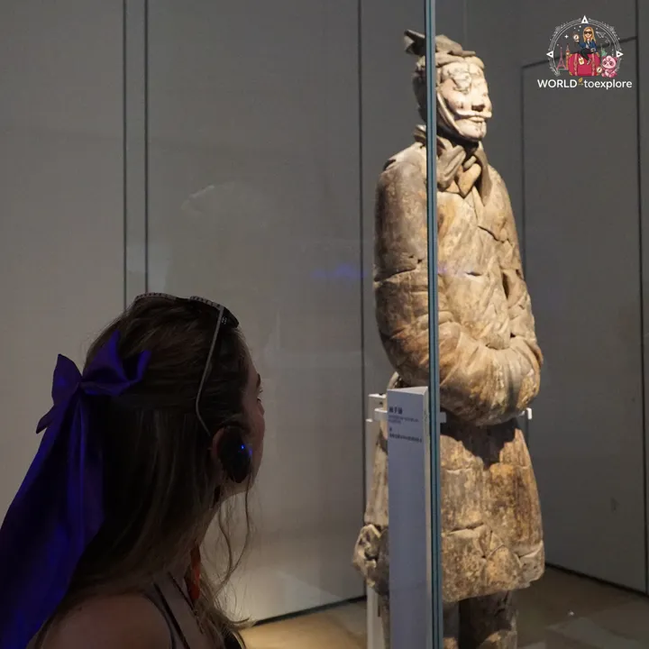 The author looking at a terracotta warrior in a case, using an audio guide