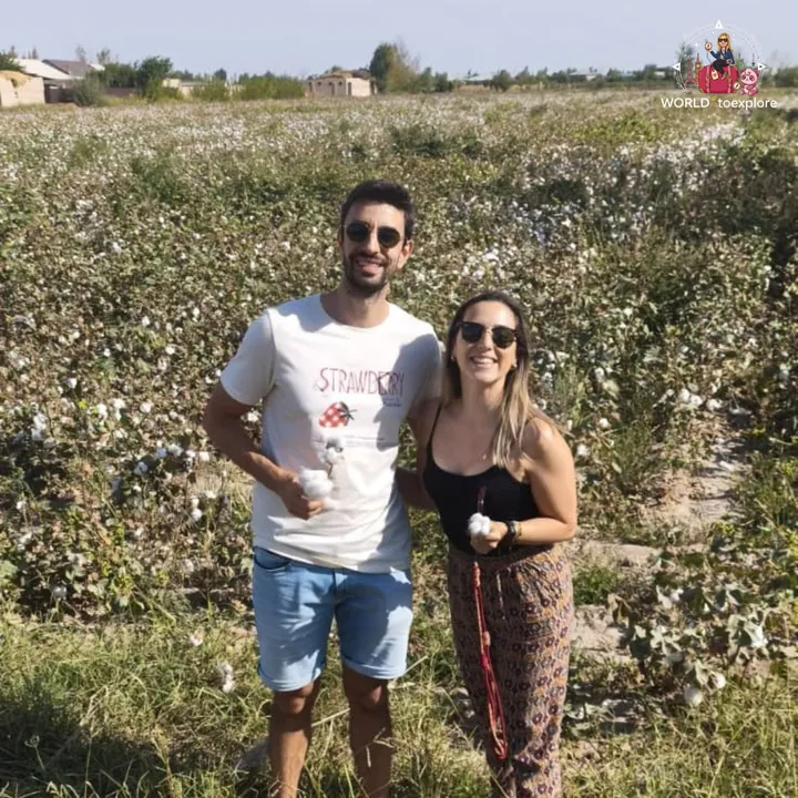 Smiling couple in a cotton field, each holding a cotton boll