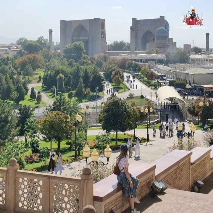 Elevated view over a garden and the domes of historic mausoleums, with the author sitting on a low wall taking photos