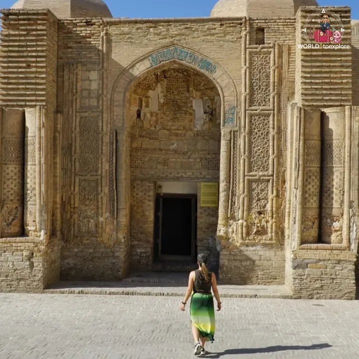 Woman walking towards the ornate brick portal of an old historic building